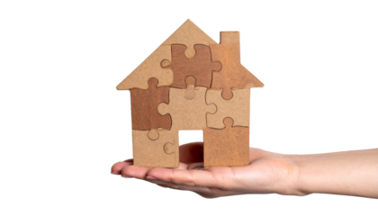A hand holding a puzzle house. The image symbolizes a hand holding puzzle piece house