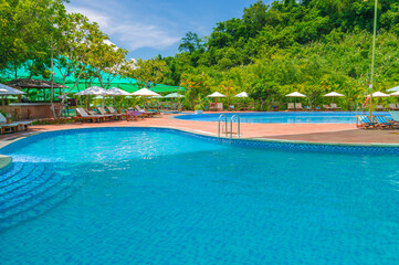 swimming pool in outdoor tropical luxury resort by sea in summer. Tourism and recreation. Landscape panorama with a pool and sun loungers and umbrellas