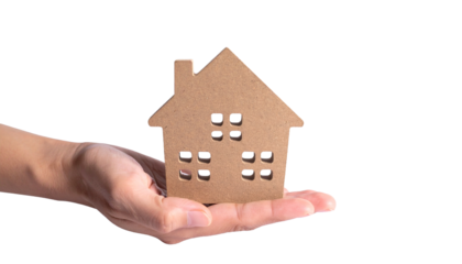 A person's hand tenderly holding a miniature house, representing homeownership and property