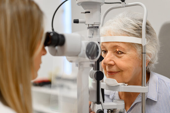Female doctor examining senior woman with slit lamp during ophthalmology clinic visit for vision checkup