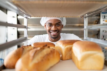 Smiling baker presenting freshly baked bread loaves in a bakery