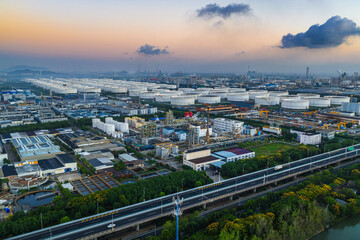 Obraz premium Aerial view of a large petrochemical industrial area with white oil storage tanks at sunset