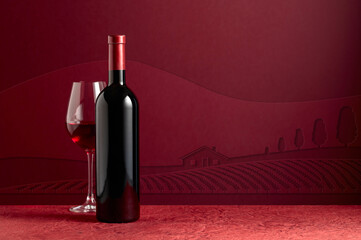 Fototapeta premium Bottle and glass of red wine on a red background.
