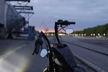 Handlebar silhouette of custom motorcycle with city lights at twilight