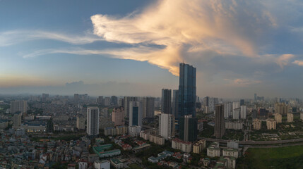 Fototapeta premium Evening panorama of Hanoi skyline with dramatic golden clouds behind a tall skyscraper.