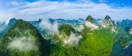 Panoramic aerial view of the majestic green karst mountain landscape with clouds and fog on a sunny...