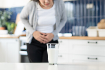 Lactose intolerant, Close-up hands of person holding a glass of milk and feeling stomach pain.