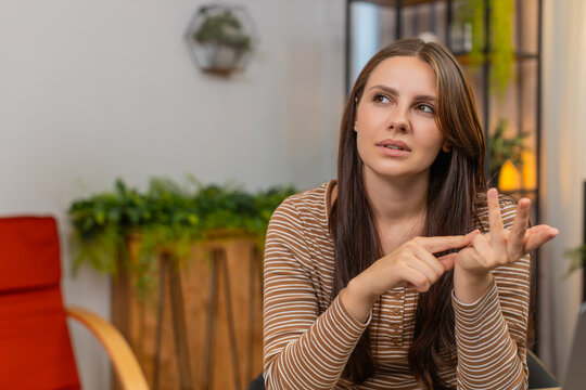 Young woman at home counts tasks on fingers folds digits and checks done list with calm focus. Caucasian girl at desk reviews progress tallies numbers writes note and plans next steps with quiet mood - Powered by Adobe