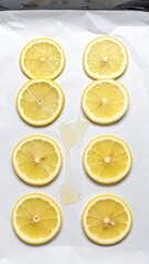 Overhead View of Yellow Lemon Slices on Baking Paper with Dripped Liquid