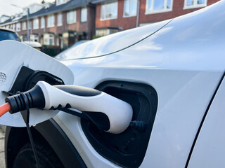Electric vehicle charging station with a close-up of a charging plug inserted into the car, showcasing modern technology and sustainable energy solutions for transportation