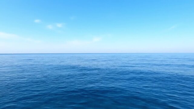 Endless expanse of the calm deep blue sea stretching to the distant horizon under a peaceful light blue sky, a serene nature background