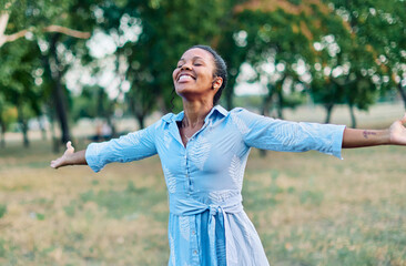 Happy young black woman meditating and daydreaming and relaxing and having fun in nature outdoors