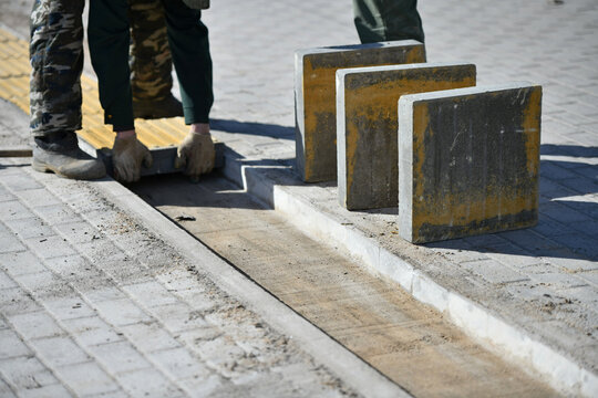 A man lays paving slabs to build a road for pedestrians.