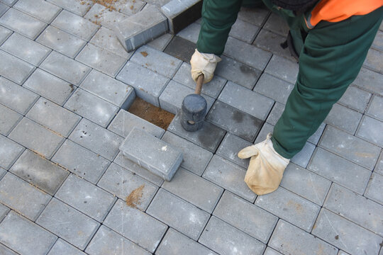 The builder levels the paving slabs with a hammer.