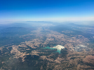 Aerial view of a vast landscape featuring mountains, valleys, and a shimmering lake, showcasing the beauty of nature and the intricate patterns of the earth's surface