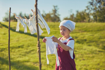 Charming girl washing clothes in the garden. Retro portrait