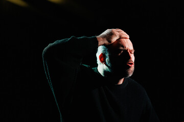 Fototapeta premium Emotional actor in sweatshirt rehearsing on stage with black background 