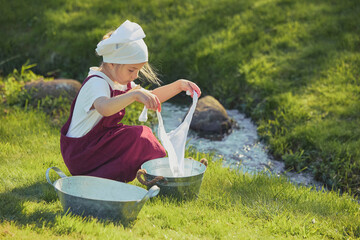 Charming girl washing clothes in the garden. Retro portrait