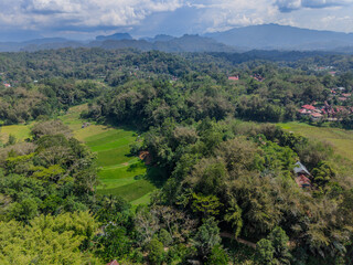 Fototapeta premium Aerial view of lush green hills, rice fields, and traditional villages in Tana Toraja, Indonesia. 