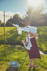 Charming girl washing clothes in the garden. Retro portrait