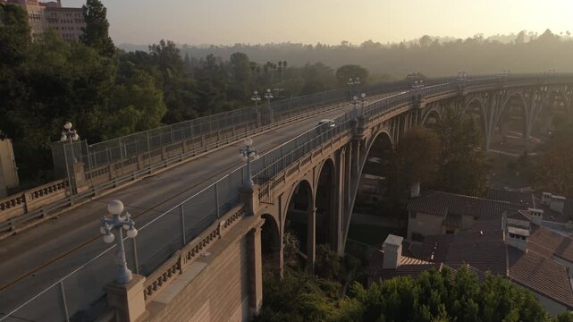 sunset flying along Pasadena's Colorado St. Bridge as car and cyclist pass