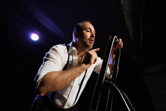 Adult actor playing role near ladder on theater stage 