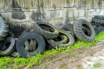 Old Tire Pile Against Weathered Wall Creates Industrial Scrap Yard Vibe, Rustic and Urban