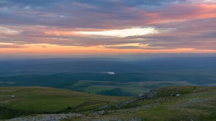 Beautiful landscape with green hills and colorful clouds at sunset, a scenic vista