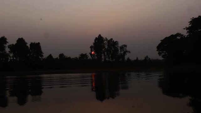 Evening Sunset, Red boll Silhouette photography background.  The bright disk of the Sun is in the sky, which is painted in pink, yellow, orange colors. Trees rise up all around.close-up video