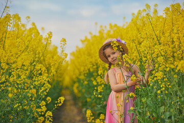 charming child in sundress in a rapeseed field