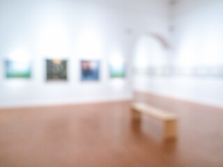 Abstract blurry image of art gallery with paintings on wall and wooden bench, symbolizing artistic perception, memory distortion, imagination, minimalism, and creative atmosphere in exhibition space.