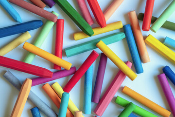 Different colorful pastel crayons on white paper, flat lay