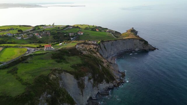 Golden hour illuminates the rugged Asturian coastline, revealing dramatic cliffs, hidden coves, and lush forests. A scenic path winds along the clifftops.