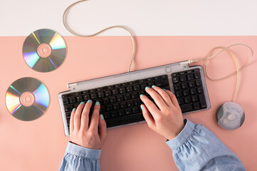 Nostalgic Computer Scene Featuring Hands Typing, Wired Keyboard and Mouse and CDs