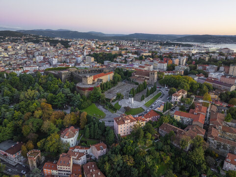Aerial view of a historic castle and cityscape blending with the vibrant greenery under the soft glow of sunset at Piazza Libert&Atilde;&nbsp;, Trieste, Friuli-Venezia Giulia, Italy.