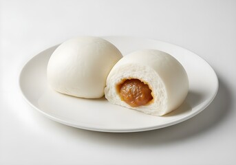 Two soft white steamed lotus seed buns with smooth surface, one slightly opened showing sweet lotus paste filling, placed on a white plate, isolated on white background.
