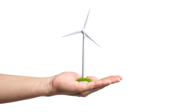 A hand holds a miniature wind turbine on a bed of green