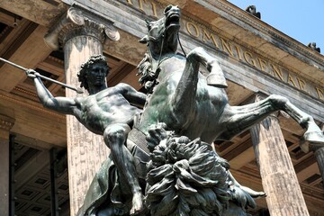 Bronze statue of a warrior on a horse hunting a lion with a spear in front of the entrance of Altes...