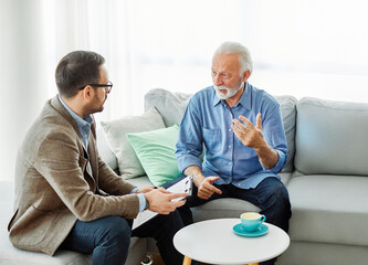 Senior man having a meeting with an agent, businessman, salesperson or doctor in his office
