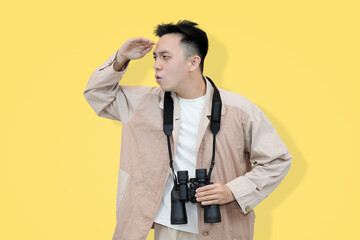 man with binoculars looking into distance against yellow background