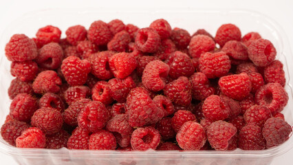 Raspberry in plastic container isolated on white background.