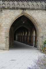 Naklejka premium Gothic stone arcade in Dinan, Brittany, France. Elegant pointed arches and intricate details showcase medieval architecture and historic charm in this peaceful architectural passage