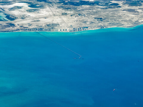 aerial landscape view of Saudi Arabian coastline near Ras Tanura with industrial plants for oil and gas production and a very long pier that extends far into the Persian Gulf