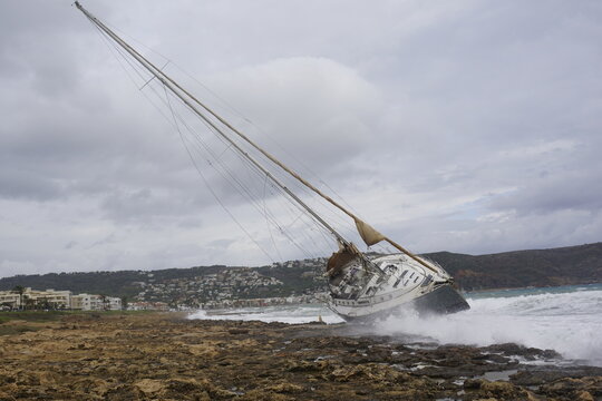 Velero encallado en la costa rocosa durante un d&iacute;a nublado

