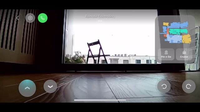First-person view from a robotic vacuum cleaner navigating a modern home, showing the smart home application interface with a digital map of the apartment for remote controlling and floor cleaning