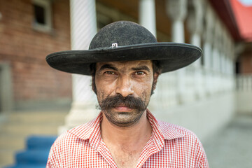 Portrait of a romani tinker with a distinct hat and mustache, facing the viewer with an intense gaze
