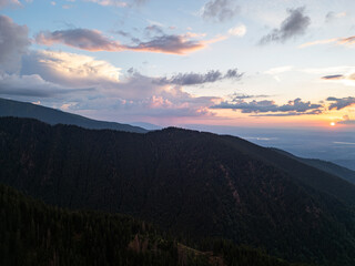 Aerial drone view of mountain ridge and forest at colorful sunset sky