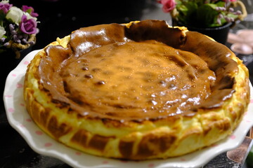 Close-up of San Sebastian Cheesecake. Homemade, toasted, delicious San Sebastian dessert made with cream cheese. Cheese desserts. Delicious San Sebastian and pink roses in a cake display case.
