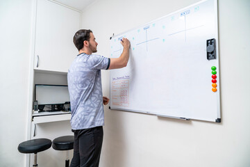 Physiotherapist writing treatment plan on whiteboard in clinic