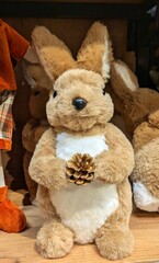 Muñeco de conejo sujetando una piña de pie en el estante de un comercio